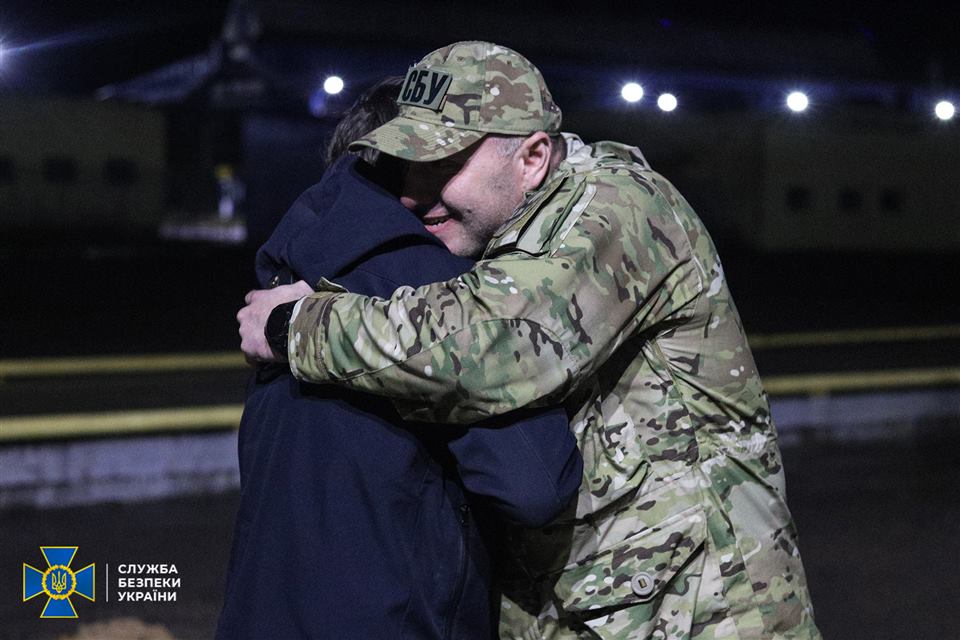 Люди обіймаються під час зустрічі після повернення до України